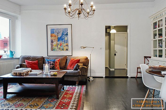 O cameră elegantă într-un apartament tipic al orașului este decorată cu perne luminoase pe canapea și covor. 