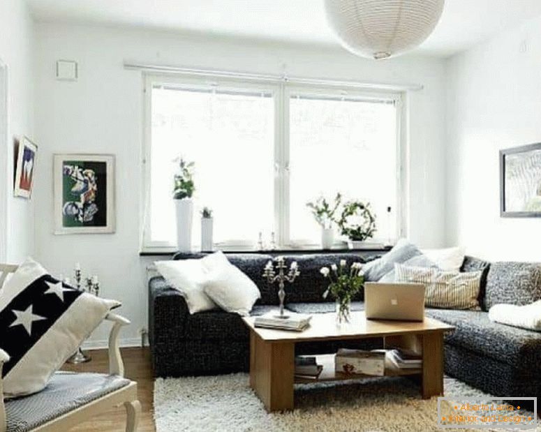 Un living mic în alb, cu o canapea de colț închis și o fereastră