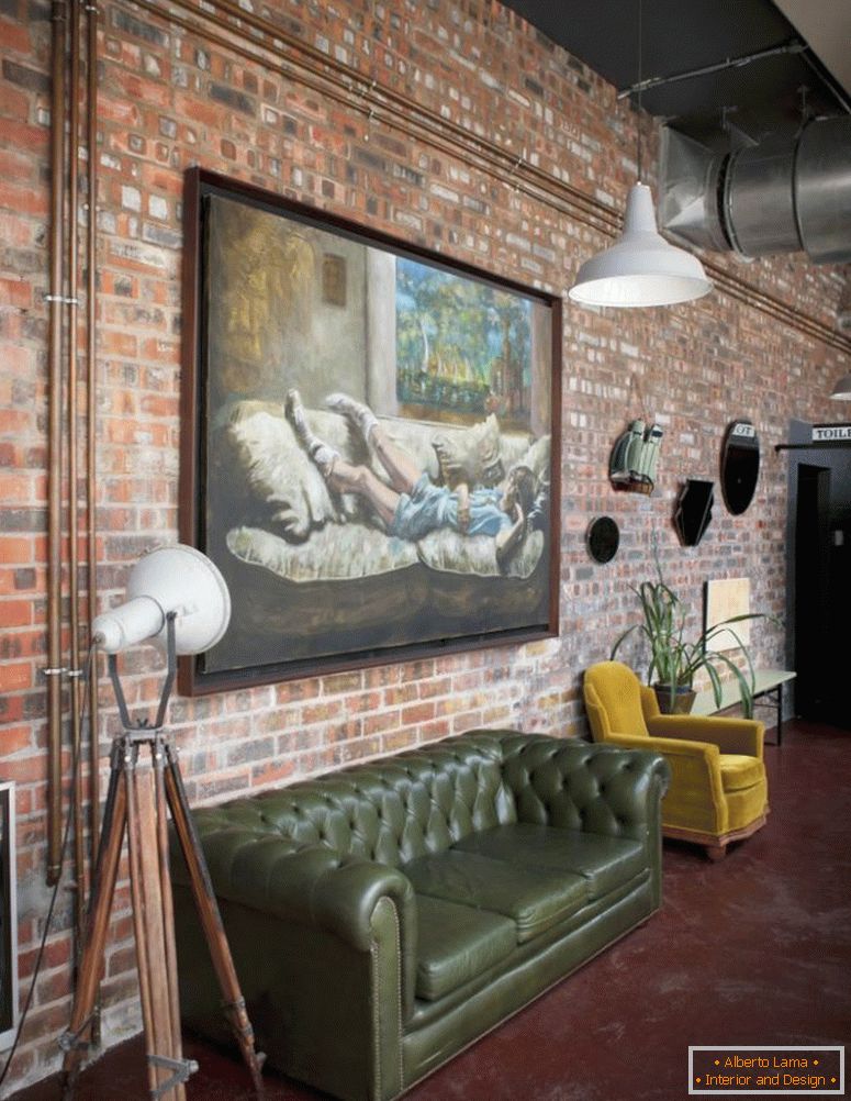 Pictură mare pe ulei pe pereți din cărămidă de apartament în stil industrial, cu canapea retro și fotoliu