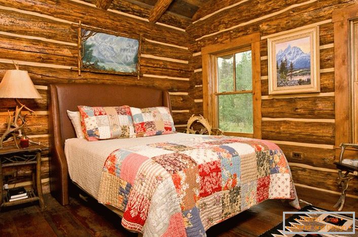 Un dormitor în stil rustic într-o cabană de vânătoare. Remarcabilă decorare a pereților cu ajutorul unei case din lemn. 