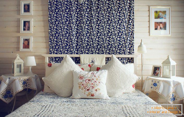 În conformitate cu stilul rustic, patul este decorat cu un număr de perne cu broderie roșie contrastantă. Noptierele sunt acoperite cu o față de masă cu flori albastre delicate.