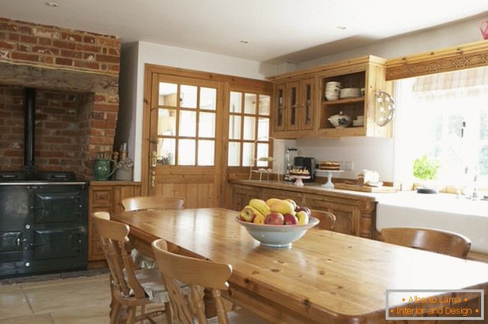 Bucătărie spațioasă în stilul țării. Mobilierul din lemn și decorarea cărămizilor deasupra aragazului conferă stilului un aspect natural și romantic.