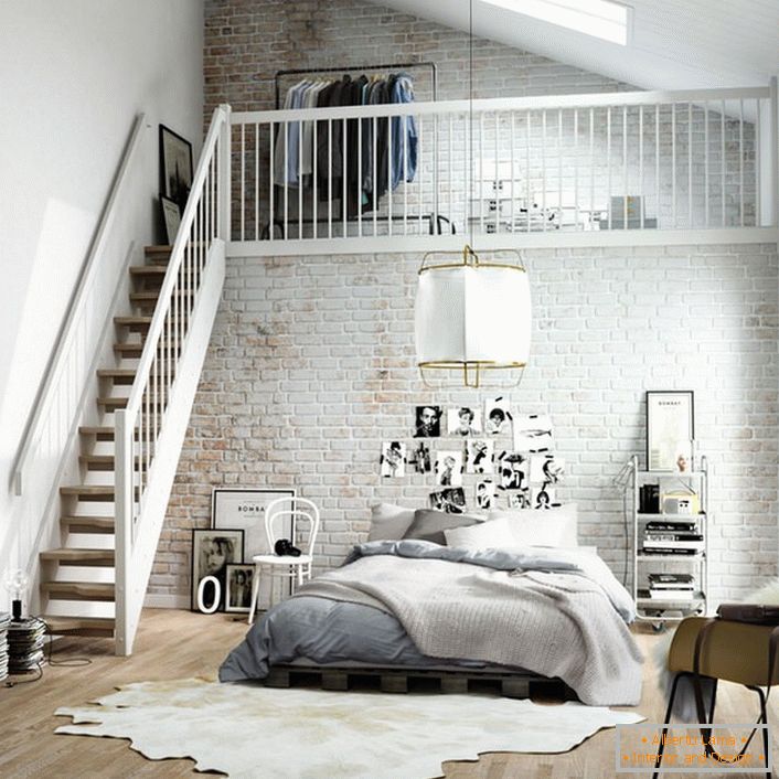 Dormitorul în stil scandinav este împărțit funcțional în două zone. O scară din lemn duce la etajul al doilea, unde pe pat se află un dressing mic.