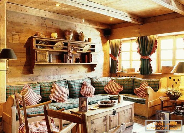 Decorațiuni de perete din lemn, perne contrastante pe o canapea moale, perdele dense cu șorțuri pe ferestre. Cameră confortabilă, în stil rustic, într-o casă de țară.