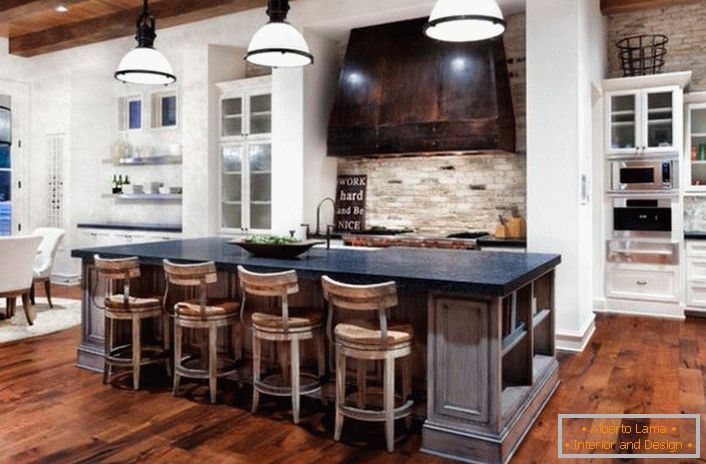 Bucătăria în stil rustic este împărțită într-o zonă de lucru și de luat masa. Finisajul alb-albastru se armonizează cu decorarea lemnului închis și a pietrei naturale.
