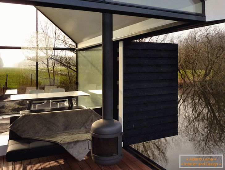 Terasa unei case mici de sticlă lângă lac din Olanda