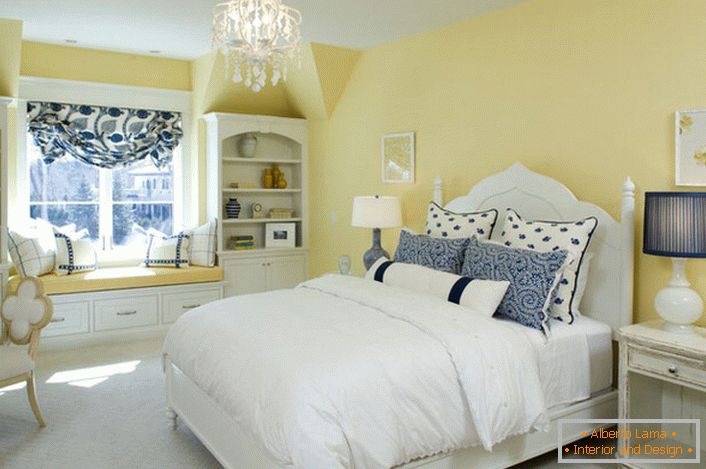 Culoarea galben decolorată a finisajului armonizează cu elementele albe și albastre ale decorului. O combinație neobișnuită este o soluție îndrăzneață pentru un dormitor în stilul țării.