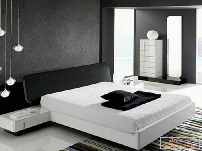 Zidul de la capul patului, decorat cu o inserție mată gri, în conformitate cu stilul hi-tech, este în armonie cu podeaua albă lucioasă.