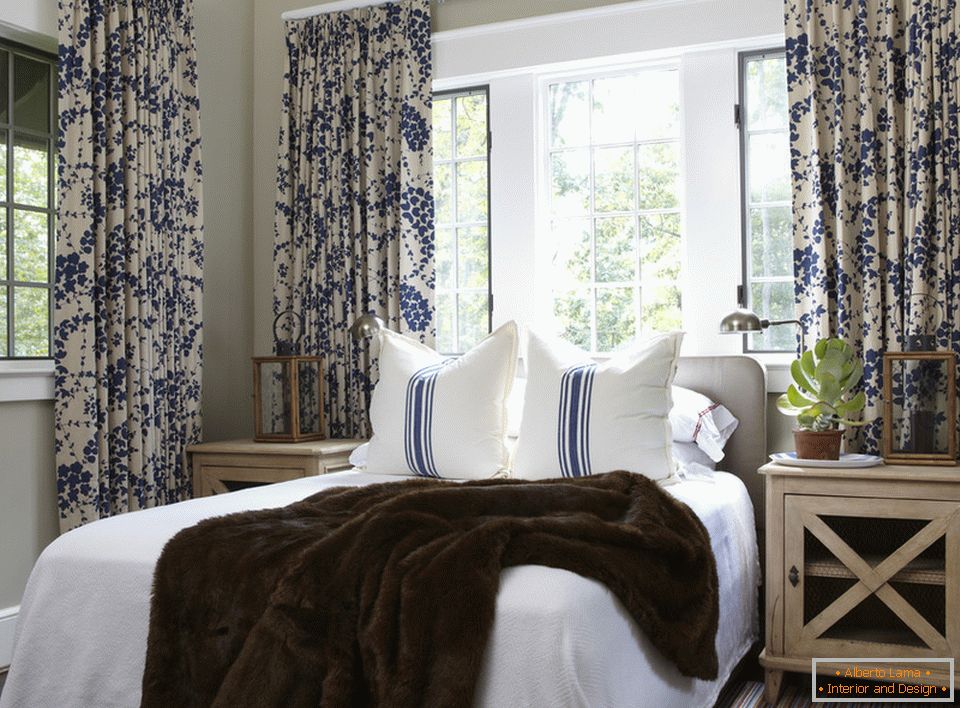 Florile albastre pe perdele și dungi de pe perne sunt combinate armonios în interiorul dormitorului