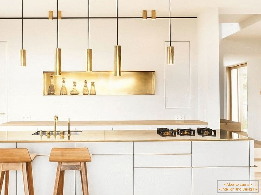 Elemente de decor de aur într-o bucătărie albă cu scaune de bar din lemn