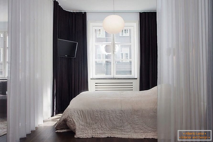 Un pat cu o perdea într-un apartament cu o cameră de 36 mp