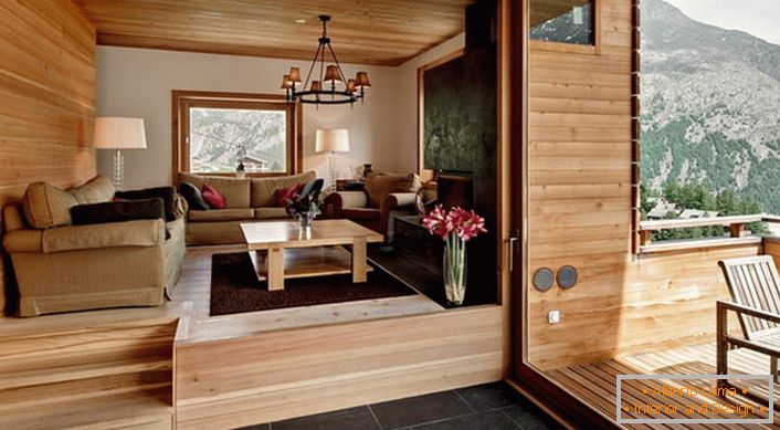 Etajul mansardei vilei cu acces la verandă este decorat în stilul unei cabane. Culoarea lemnei ușoare pare a fi profitabilă în combinație cu o placă de pardoseală maro închis.
