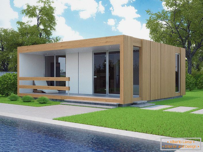 O mică casă modulară cu o piscină în curte. Designul elegant al unei case care se construiește rapid arată organic pe fundalul unei peluze scurte.