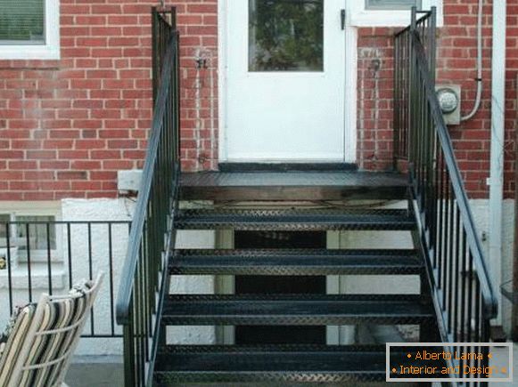 O mică verandă metalică, cu o scară în cărămidă