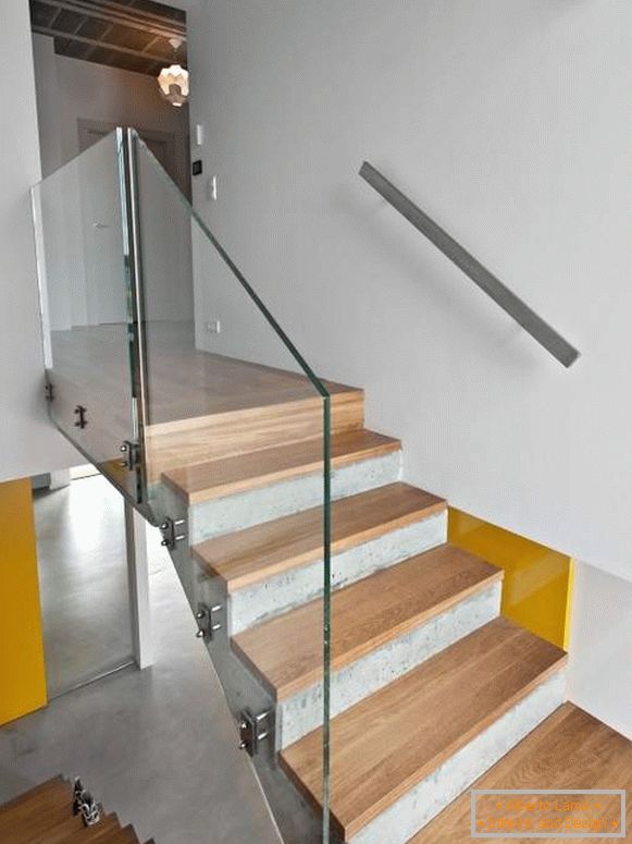 Scară de beton cu scări din lemn și balustradă de sticlă într-o casă privată