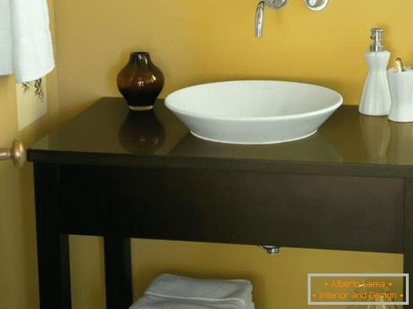 O masă de bordură sub chiuvetă în baie, pe mâini