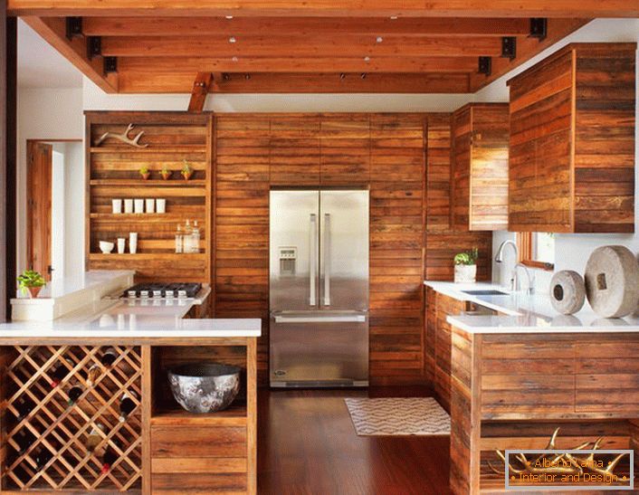 Bucătăria modernă în stil cabană este remarcabilă pentru decorarea sa laconică, cu cheie redusă. Setul de lemn fără mobilier suplimentar arată elegant și eficient.