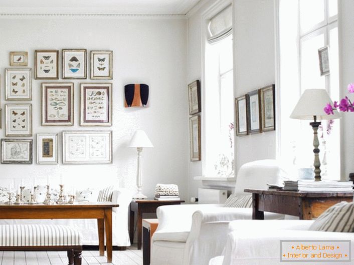 O cameră de zi confortabilă în stil scandinav este făcută în alb. Este interesant de decorat peretele cu cadre de diferite dimensiuni.