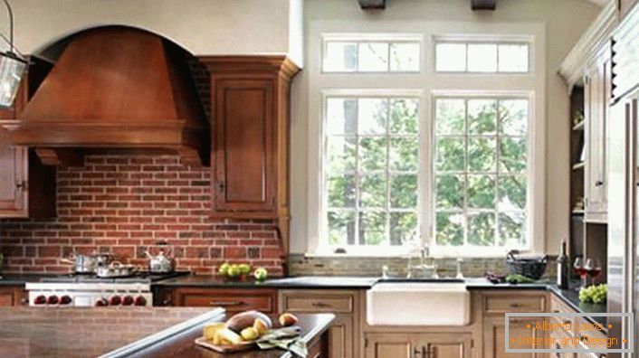 Bucătărie decorată corect, în stil rustic. Hota și dulapurile din lemn de culoare închisă sunt combinate cu un perete, prevăzut cu cărămizi.