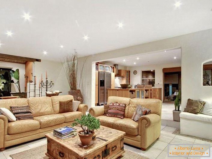 Interiorul luxos și elegant al livingului în stil mediteranean. Mobilier moale, bej lumină, iluminat selectat în mod corespunzător, podea cu gresie - mărturisesc stilul mediteranean.