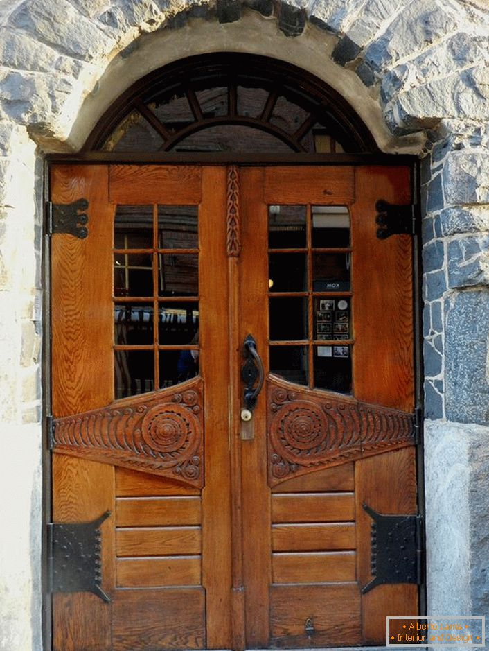 Ușile în stil Art Nouveau decorează ușa din față a unei cabane de țară cu o fațadă din piatră naturală. 