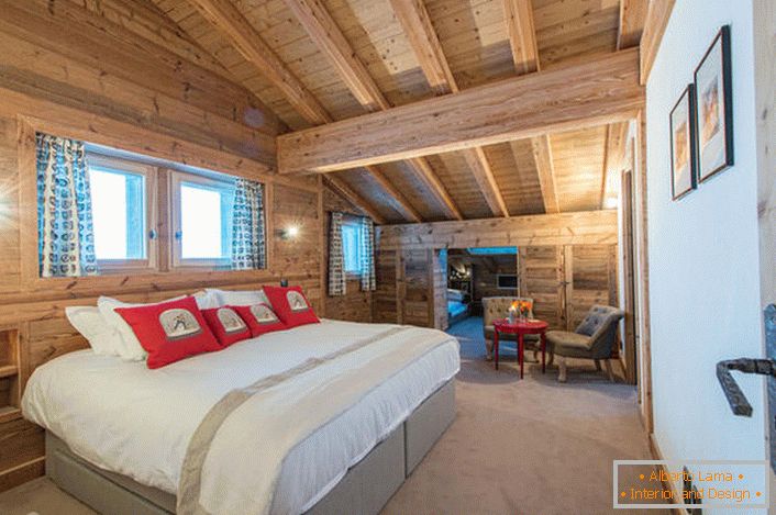 Un dormitor spațios la etajul al doilea dintr-o casă de țară dintr-o casă de lemn din lemn. В соответствии со стилем кантри искусственный свет в комнате приглушен. 