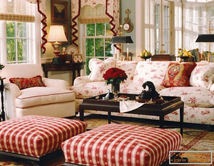 O cameră de zi simplă, modestă și confortabilă, în stil englez, într-o mică casă de țară. Accentele de roșu fac atmosfera în cameră relaxată și veselă.
