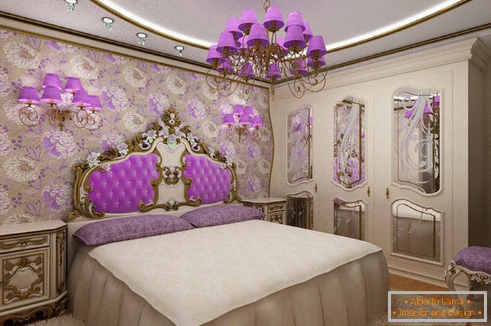 Cameră elegantă, în stil baroc, cu un accent interesant pe iluminat. Candelabrele și lămpile de nopți cu aceleași nuanțe violete, combinate armonios cu tapițeria de la spate la capul patului.